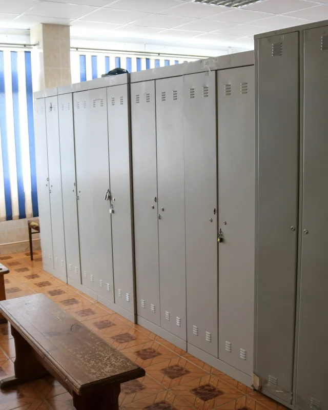 Row of grey staff lockers and a bench in an empty changing room