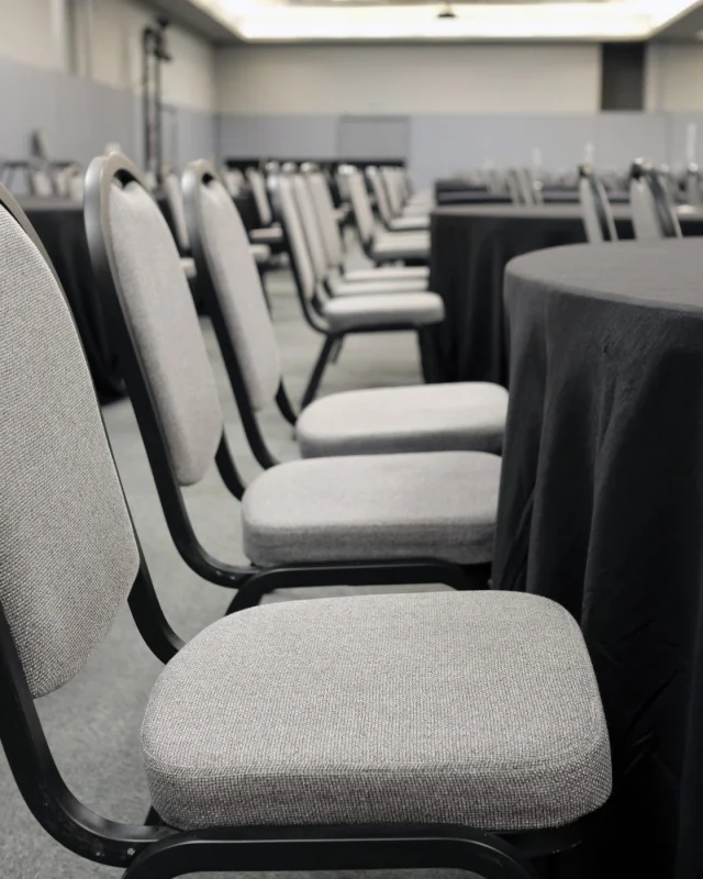Rows of grey banquet chairs set out in an empty function room