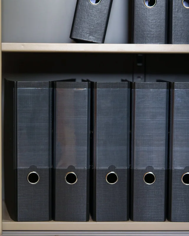 Rows of dark archive binders filling a records cabinet