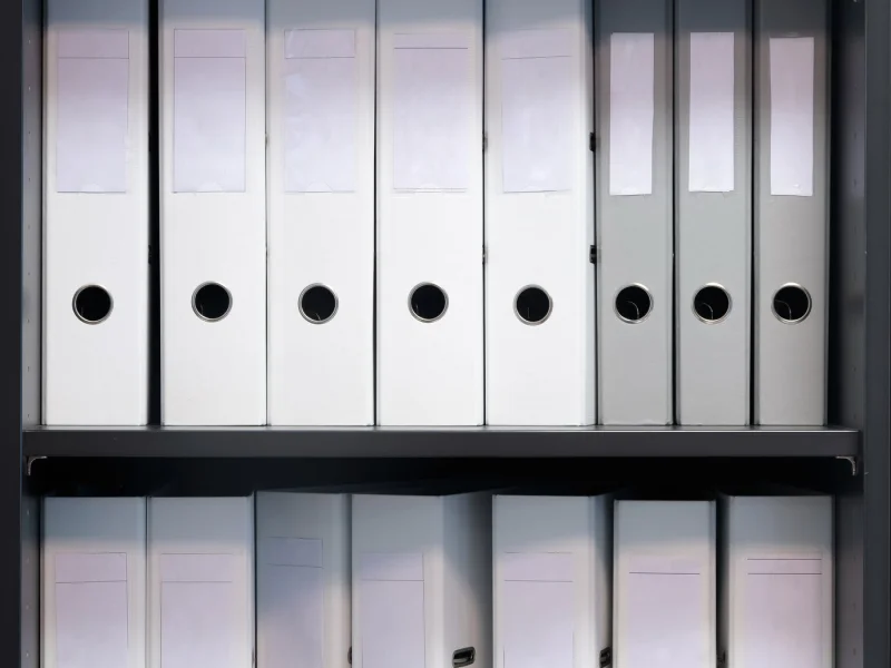Shelves of plain white record binders, spines unlabelled