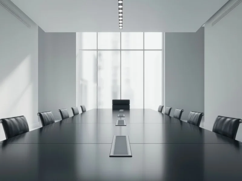 Long dark boardroom table under even light, the room empty