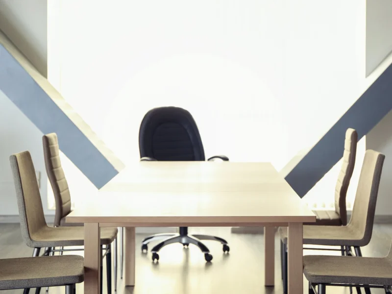 Single empty chair at the head of a long meeting table