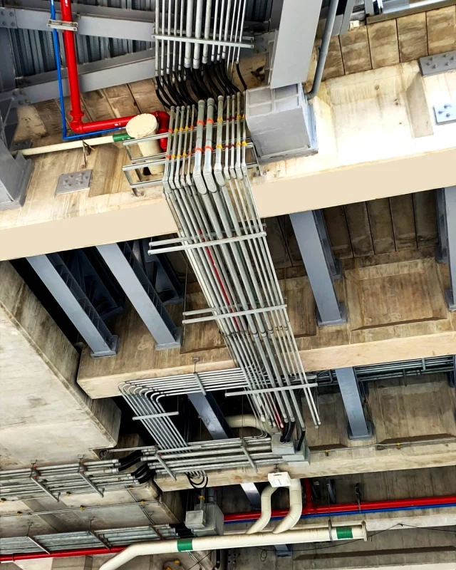Banks of electrical conduit rising through a concrete soffit on a commercial fit-out