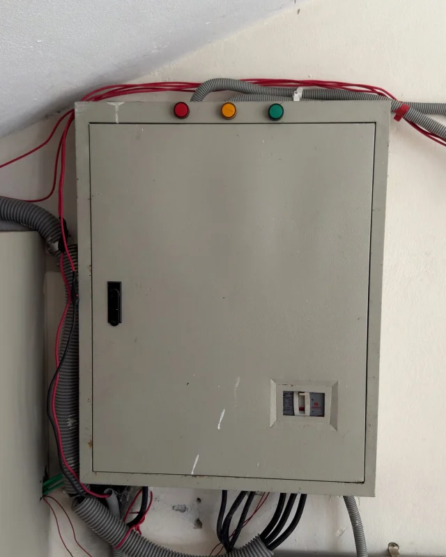 Surface-mounted distribution board with its indicator lights and wiring runs on a plant room wall