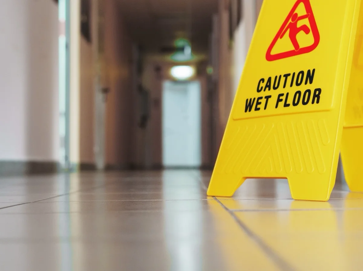 Yellow wet floor warning sign standing on a hard floor in a corridor