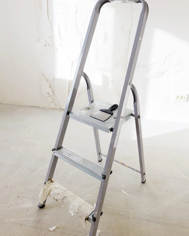 Step ladder and tools on a dust sheet in an unfinished interior