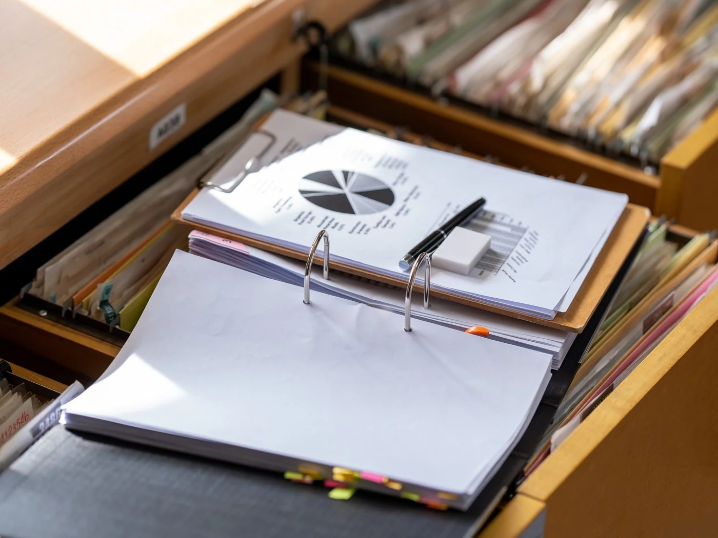 Open filing cabinet drawer with a ring binder of service records resting on the files