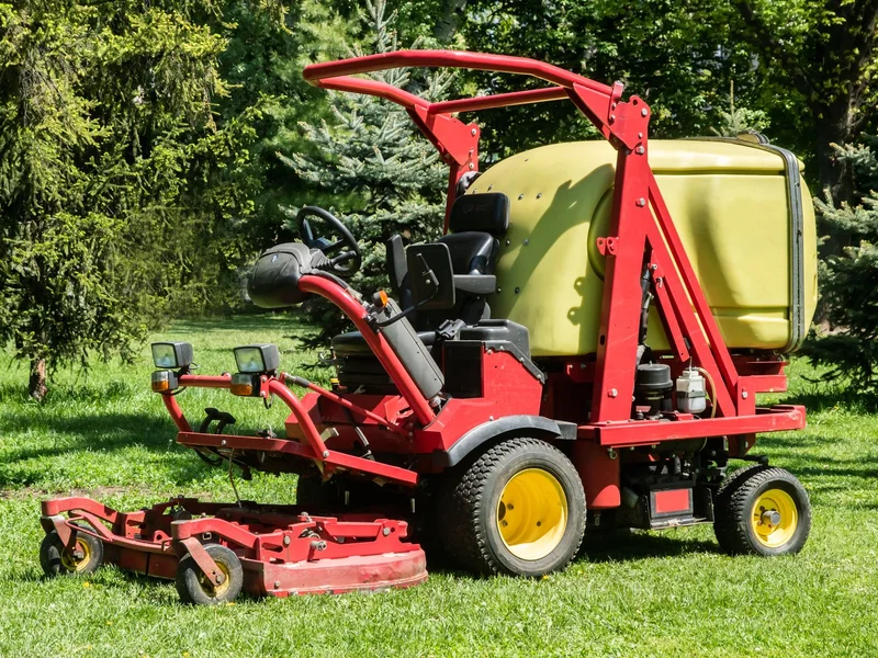 Ride-on mower and grounds equipment parked on a maintained lawn