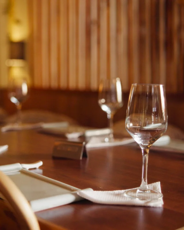 Wine glasses and place settings laid along a banquet table