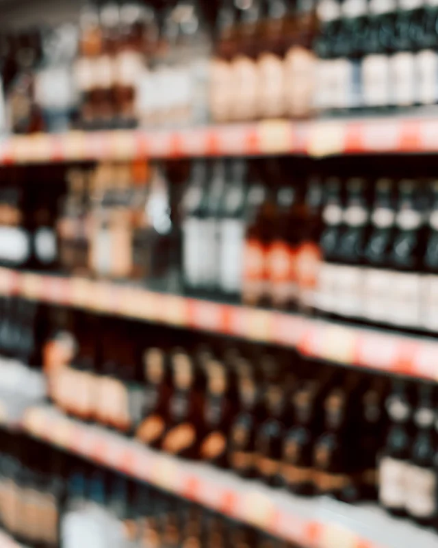 Retail shelves of bottles receding out of focus down an aisle