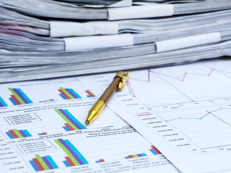 Stack of reports and a pen resting on printed charts