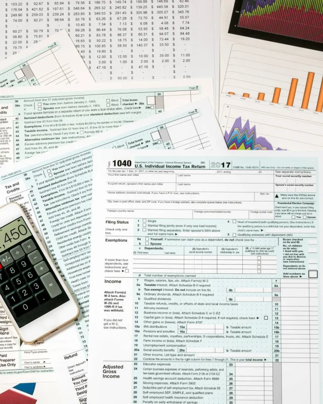 Federal tax return forms spread on a desk beside a calculator