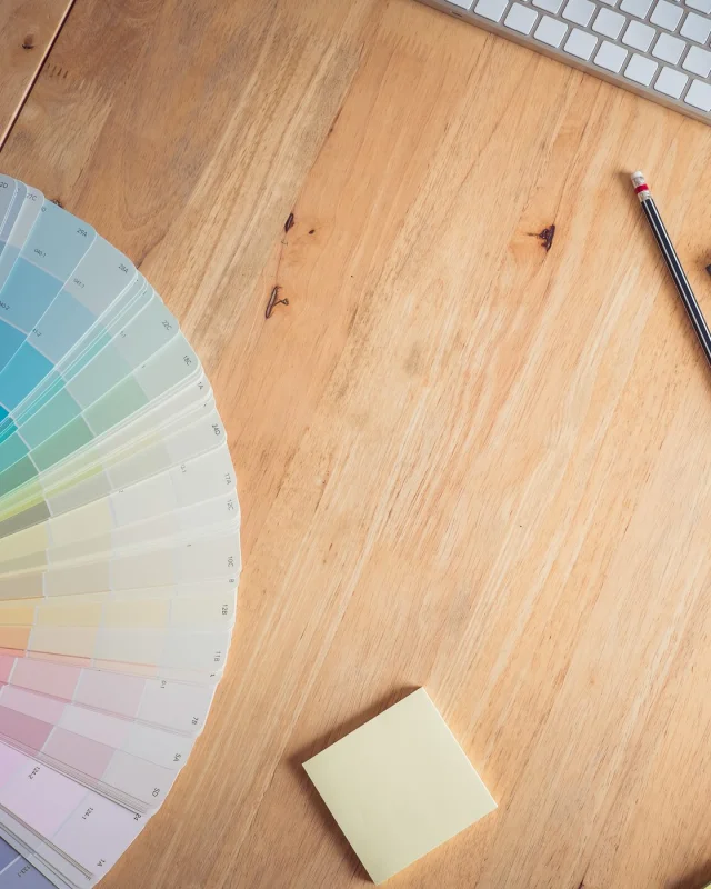Fanned colour swatch deck and a pencil on a timber studio desk