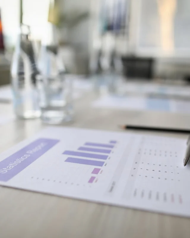 Printed figures left on a boardroom table, the room empty behind them