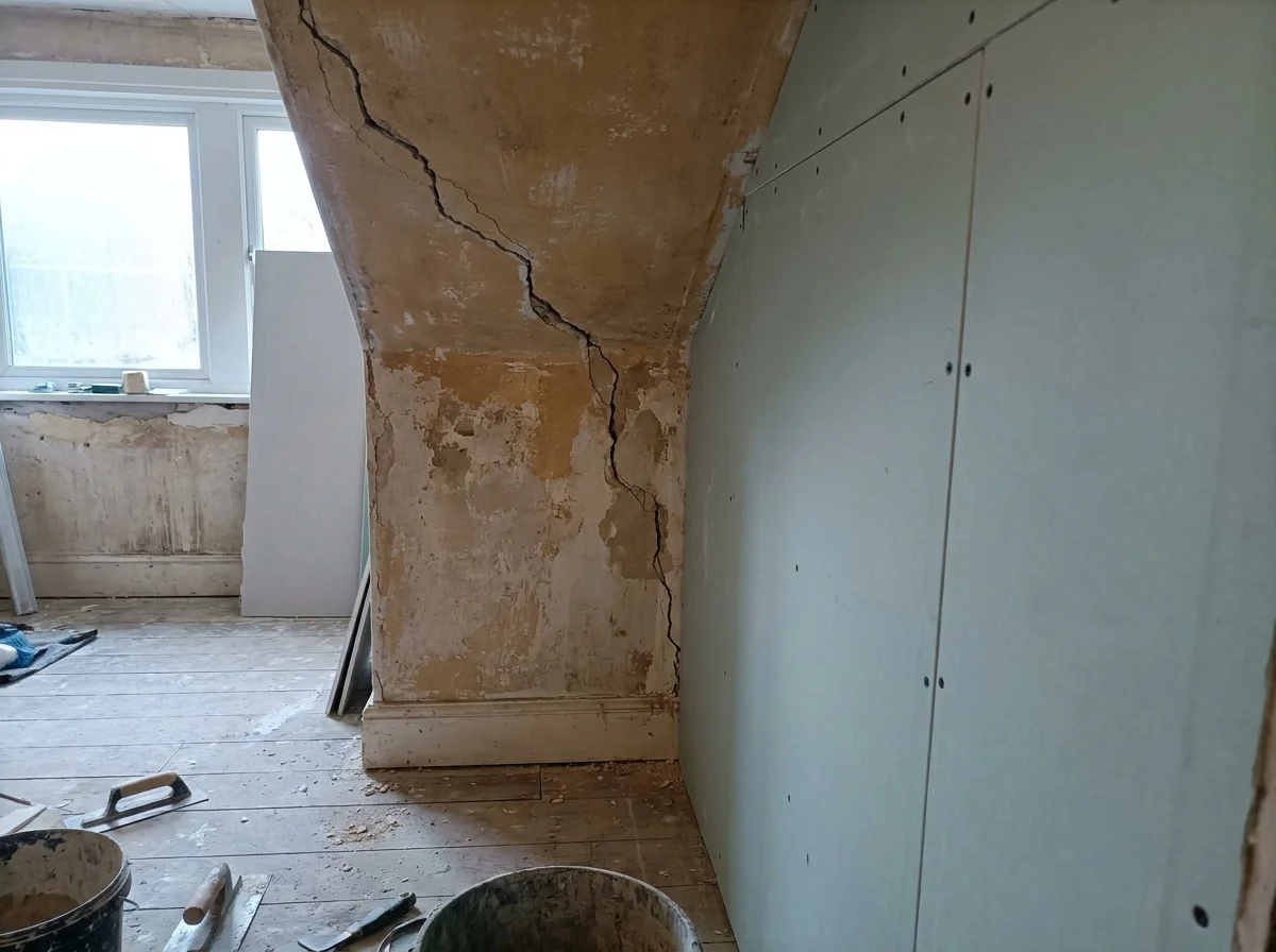 Crack running through original plaster beside a section of new plasterboard