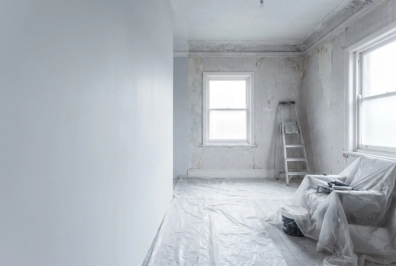 Residential room part way through renovation with dust sheets and a folded step ladder