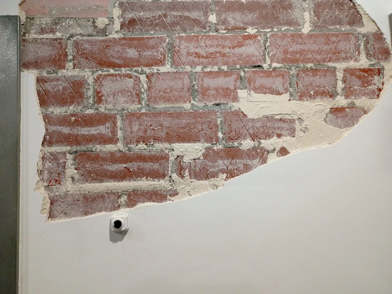 Old brickwork exposed where plaster has come away from an interior wall
