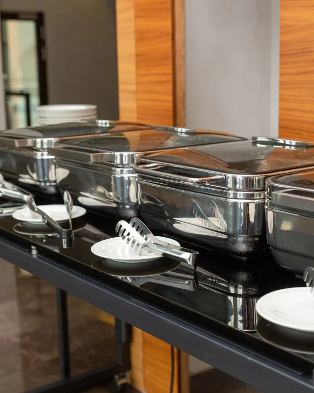 Row of closed stainless chafing dishes on a catering table