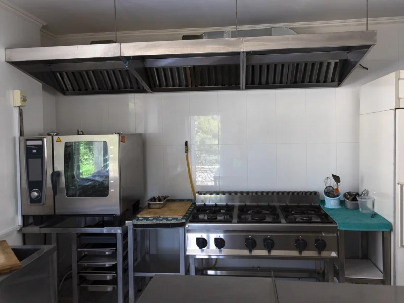 Stainless extraction canopy with baffle filters above an empty commercial range